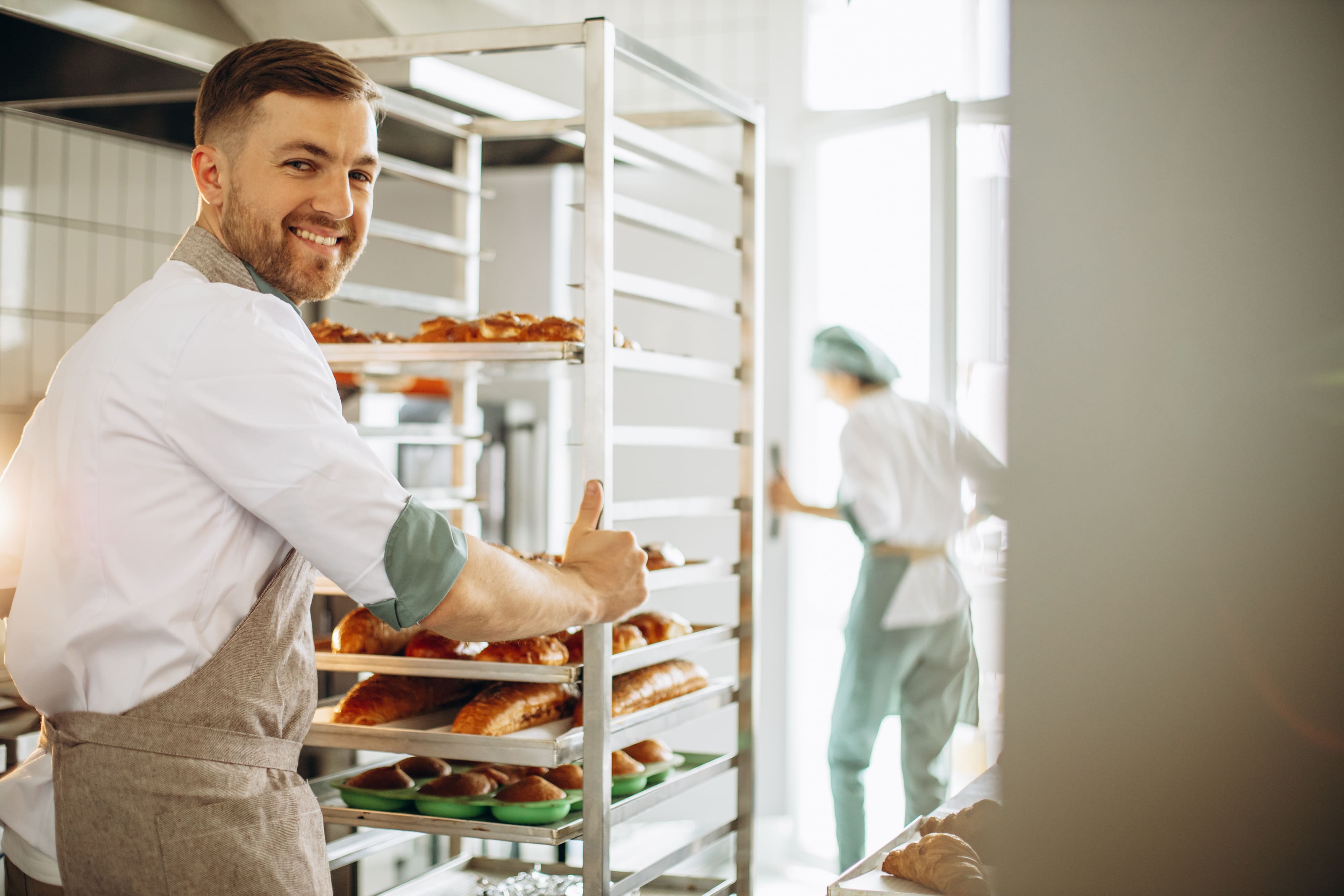 homem padeiro na cozinha pelo carrinho de pastelaria